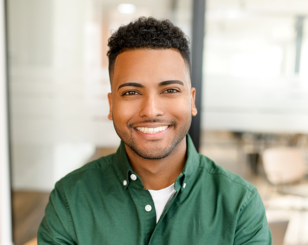 Smiling man wearing green shirt in modern dental office setting