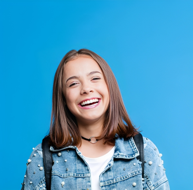 Smiling young woman in denim jacket against blue background, professional portrait