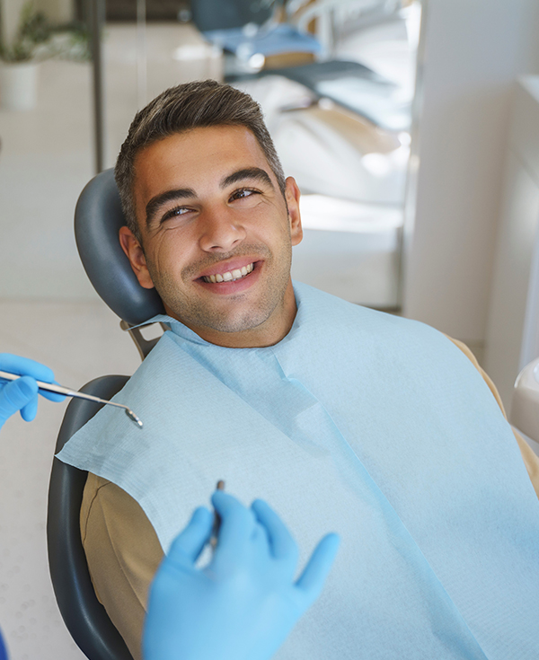 Smiling man in blue bib seated in dental chair at Aspire Dental office