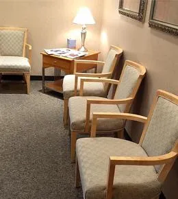 Modern dental waiting room with upholstered chairs, desk lamp, and neutral decor.