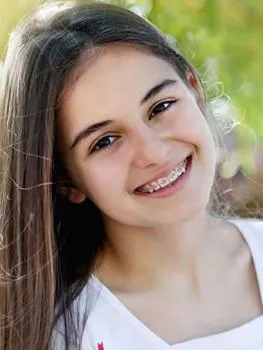 Smiling young woman with long dark hair outdoors in natural daylight setting.